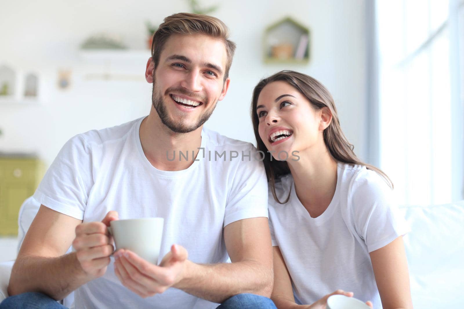 Cheerful young couple in the morning at home in the living room.