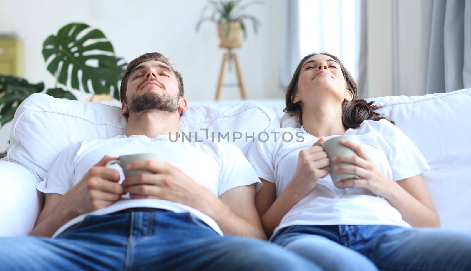 Smiling beautiful couple sitting on a sofa and dreaming about new home.