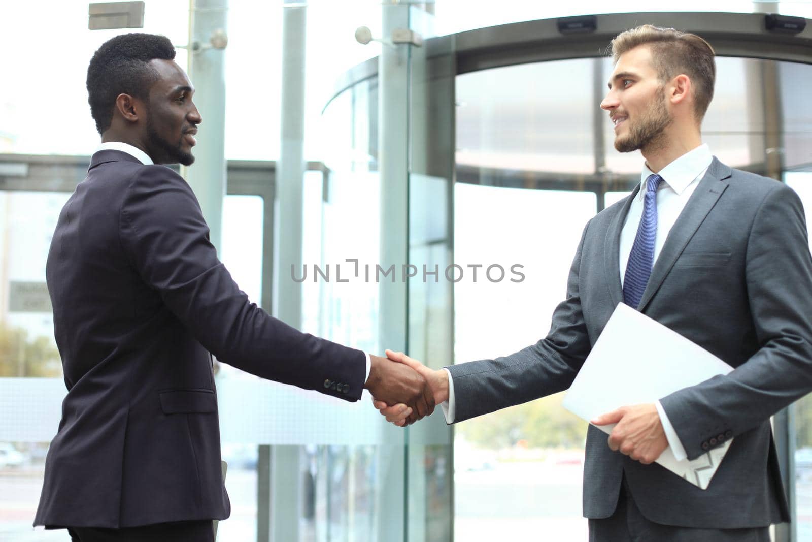 Business meeting. African American businessman shaking hands with caucasian businessman. by tsyhun