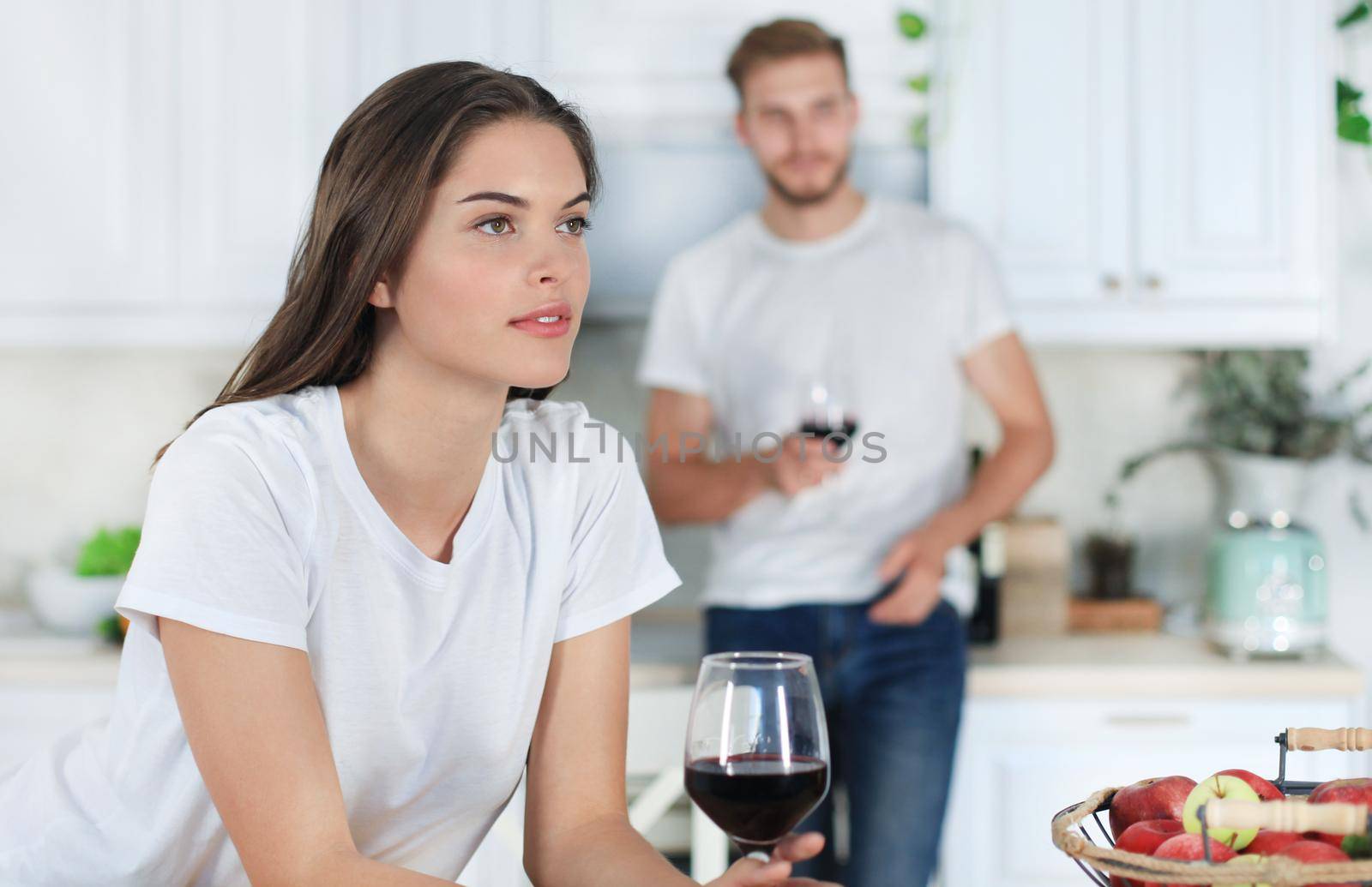 Pretty young woman drinking some wine at home in kitchen.