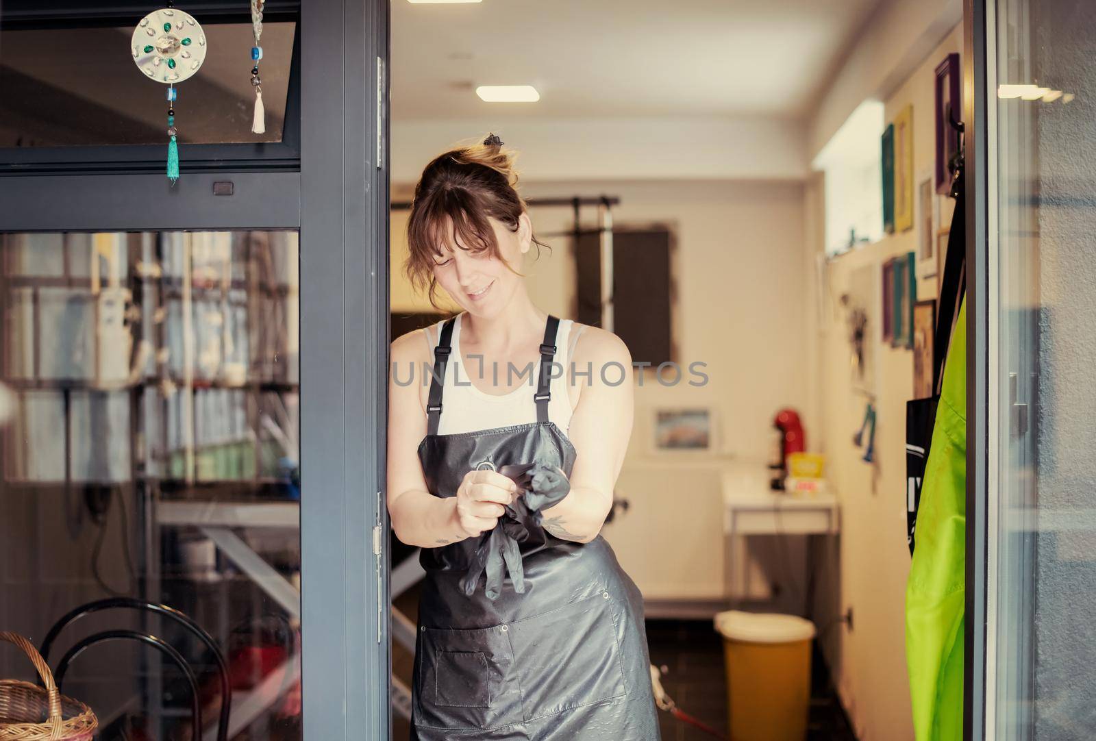 portrait of professional pet hairdresser hipster woman with tattoos while standing at the door of her beauty salon for animals