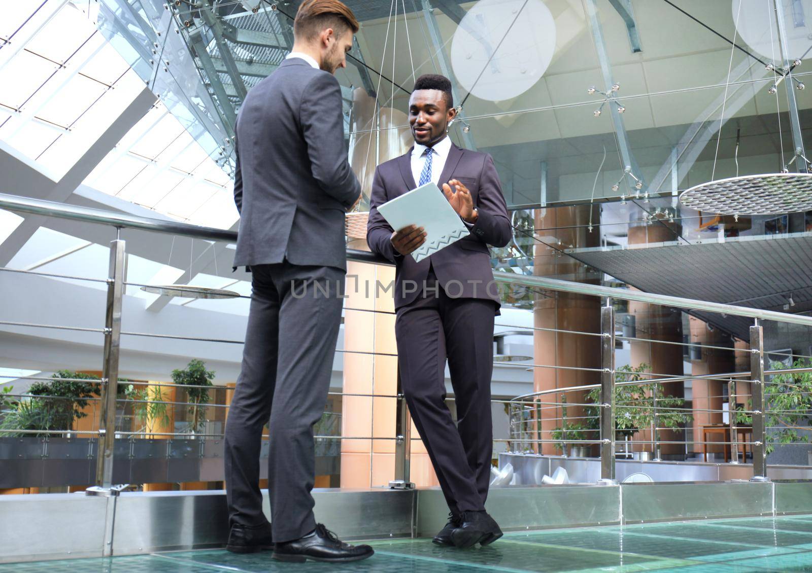 Two multinational young businessmen discussing business at meeting in office. by tsyhun