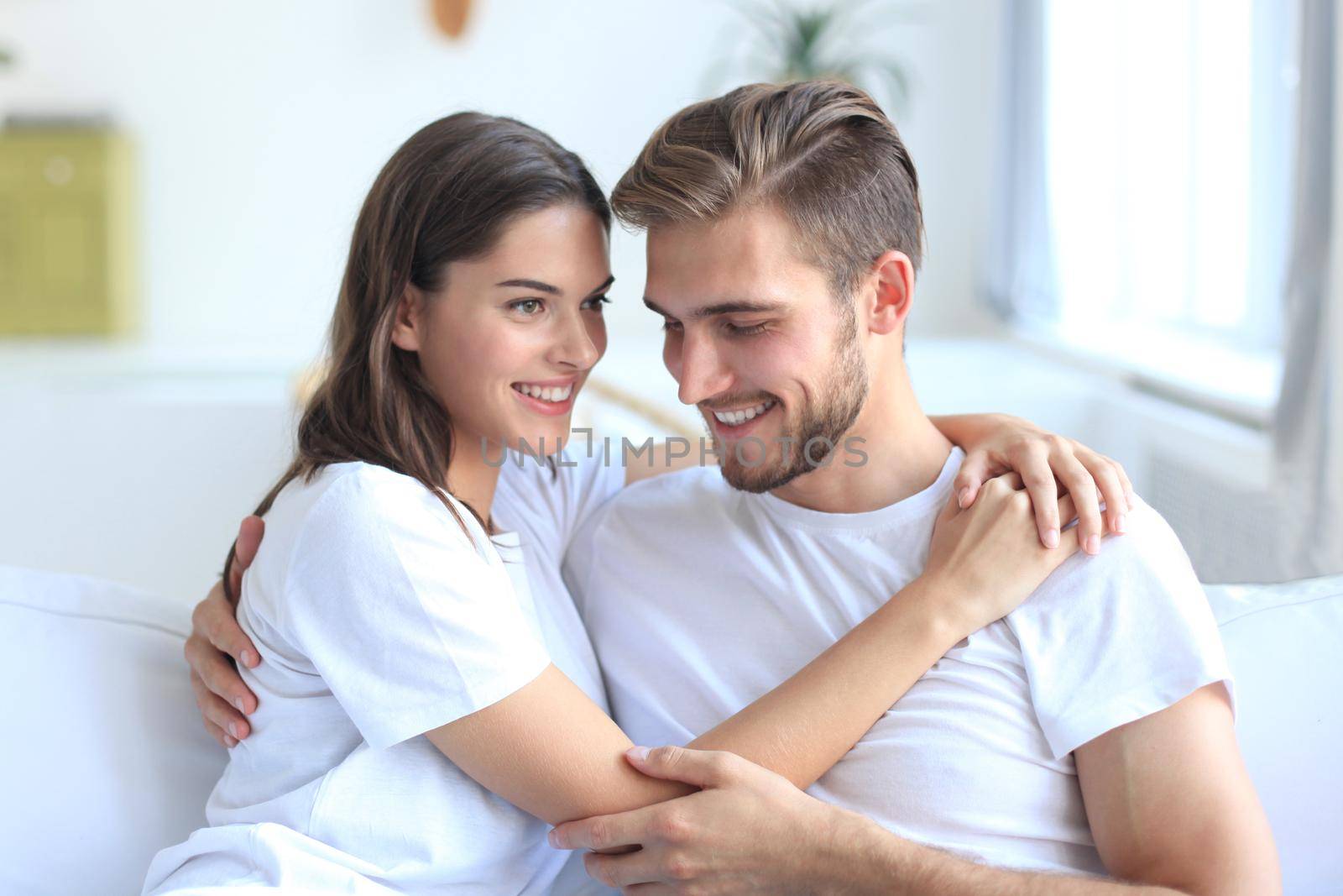 Happy young couple hugging and looking at each other at home interior.