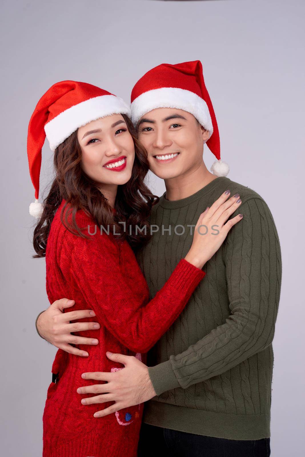 Happy young lovers in knitted woolen clothing hugging and looking together.