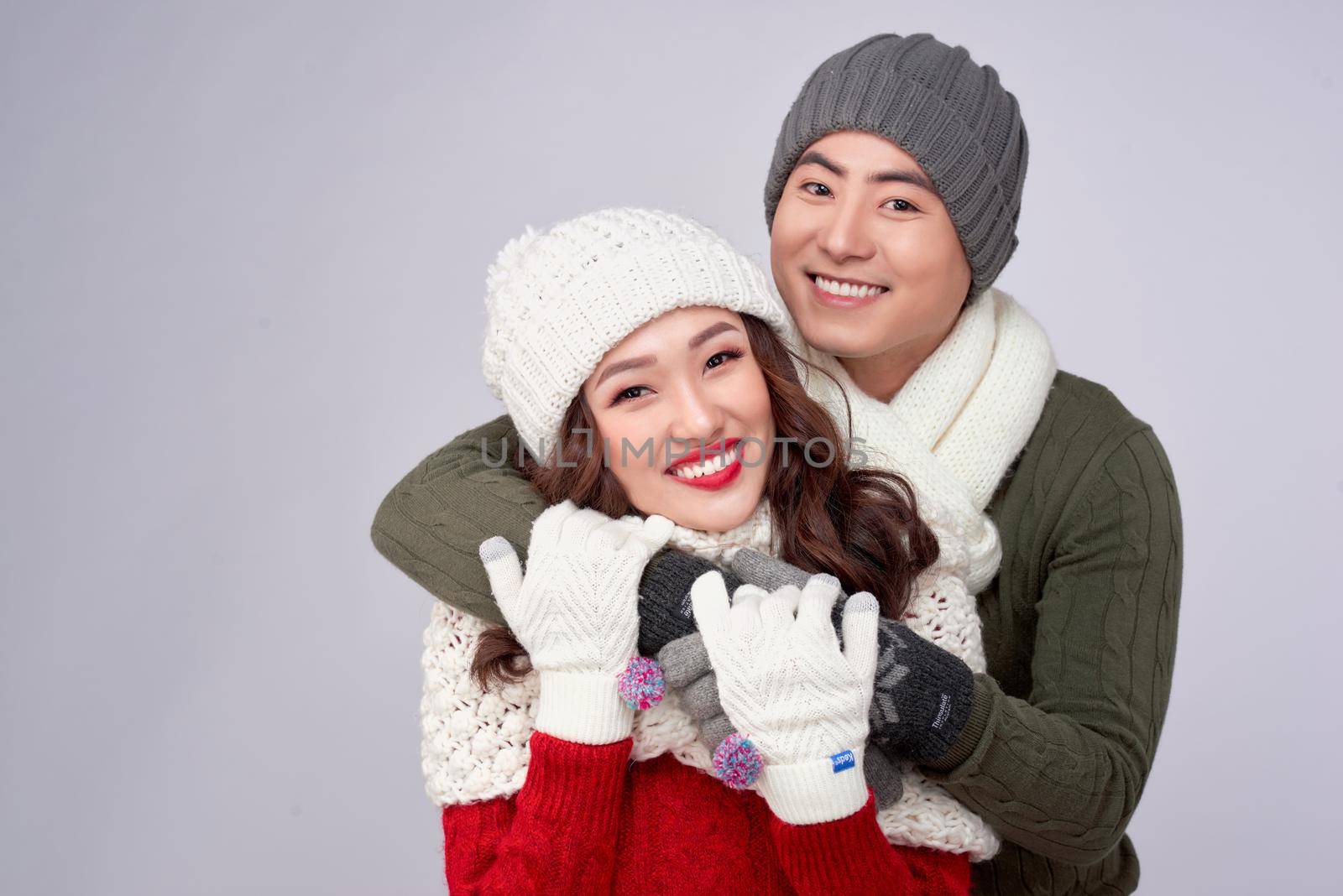 Happy young lovers in knitted woolen clothing hugging and looking together. by makidotvn