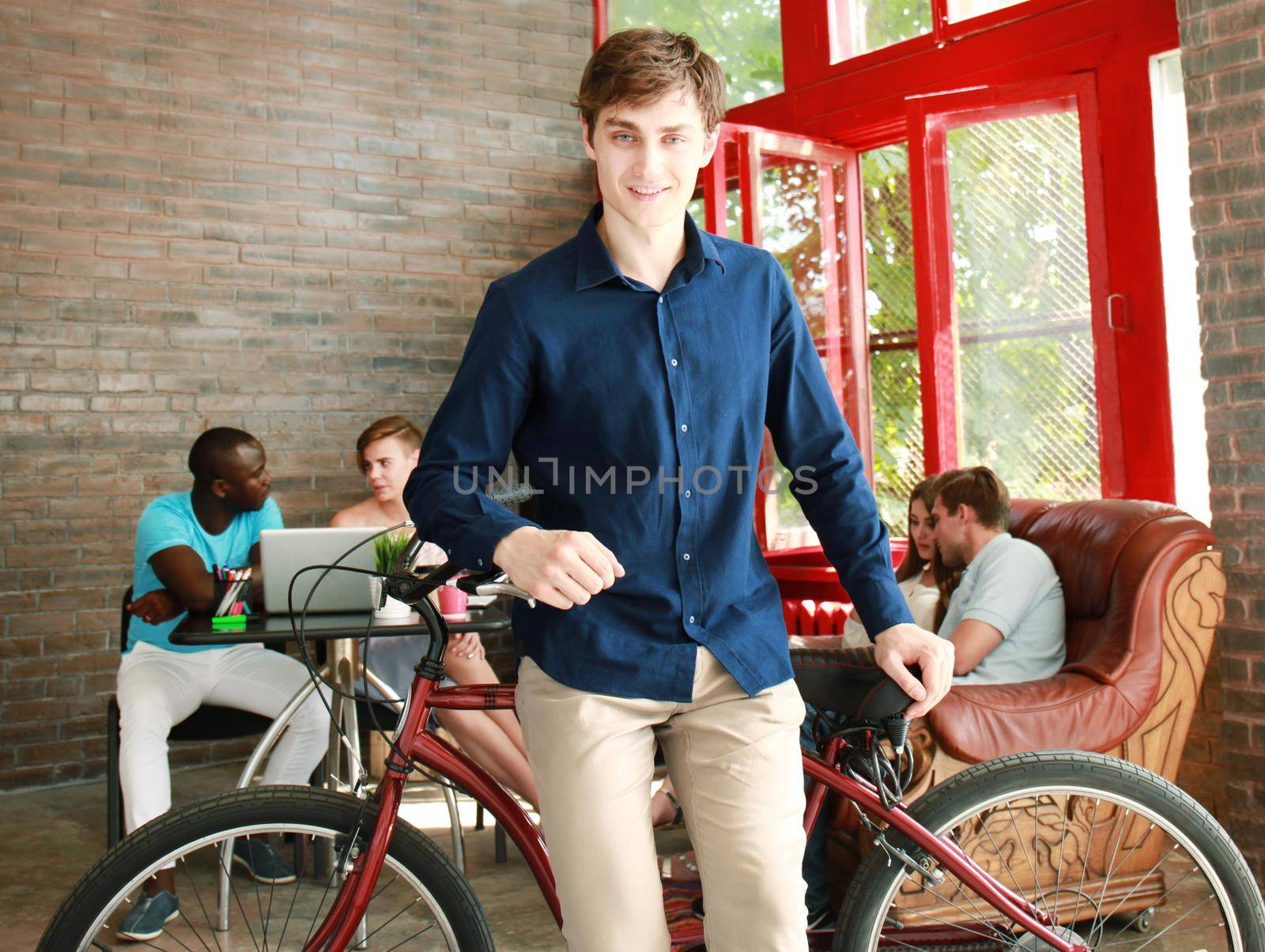 Young man sitting on a bicycle in a modern office