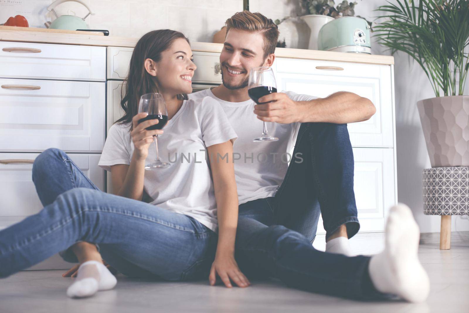 happy young couple sitting on floor in kitchen at home. by tsyhun