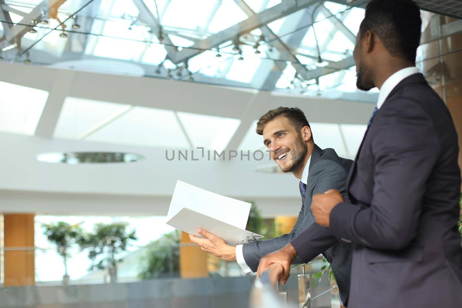 Two multinational young businessmen discussing business at meeting in office.