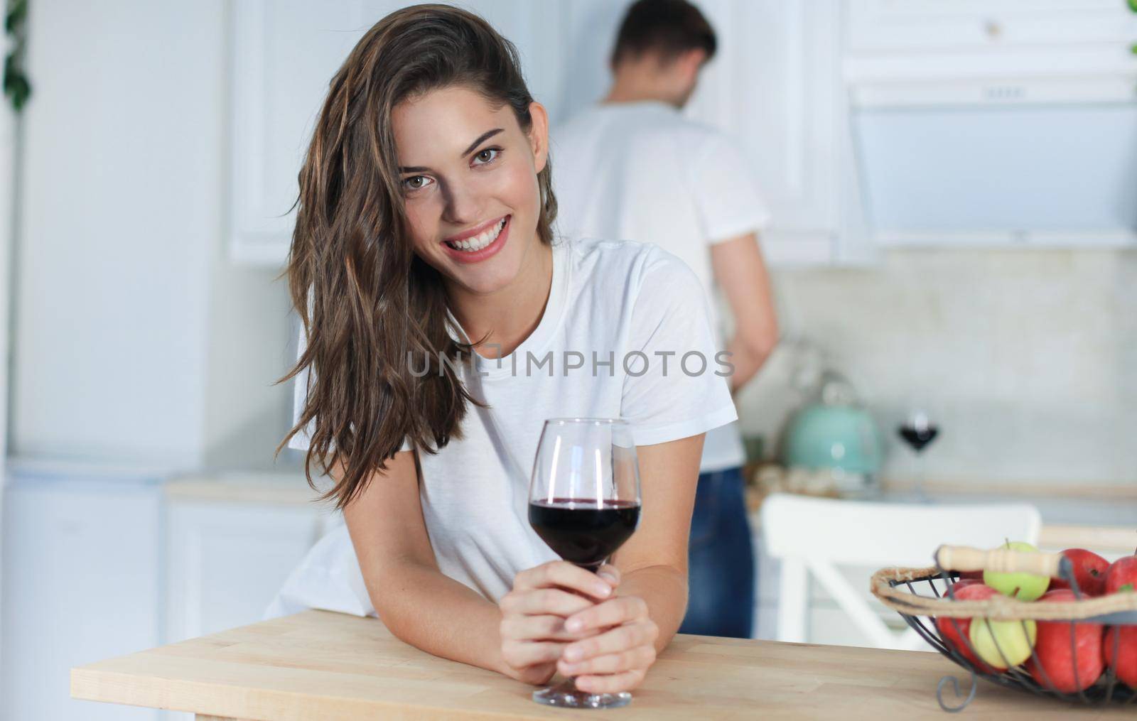 Pretty young woman drinking some wine at home in kitchen.