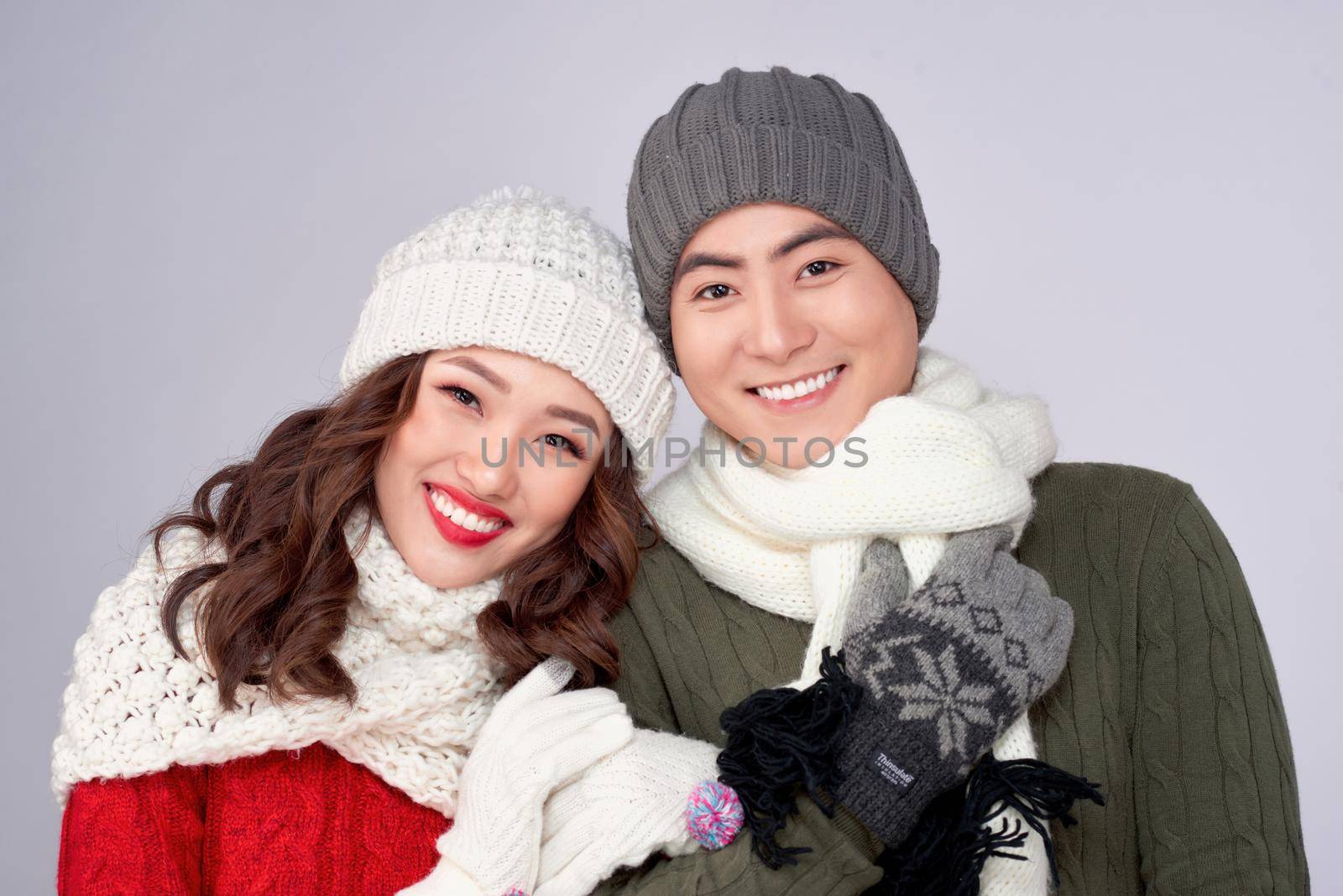 Happy young lovers in knitted woolen clothing hugging and looking together.