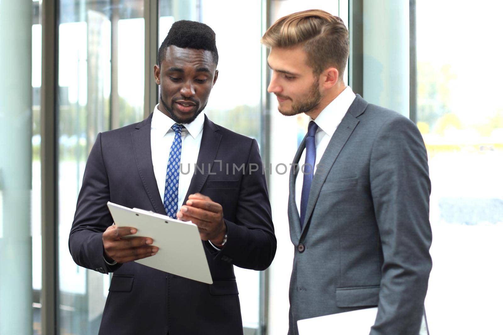 Two multinational young businessmen discussing business at meeting in office. by tsyhun