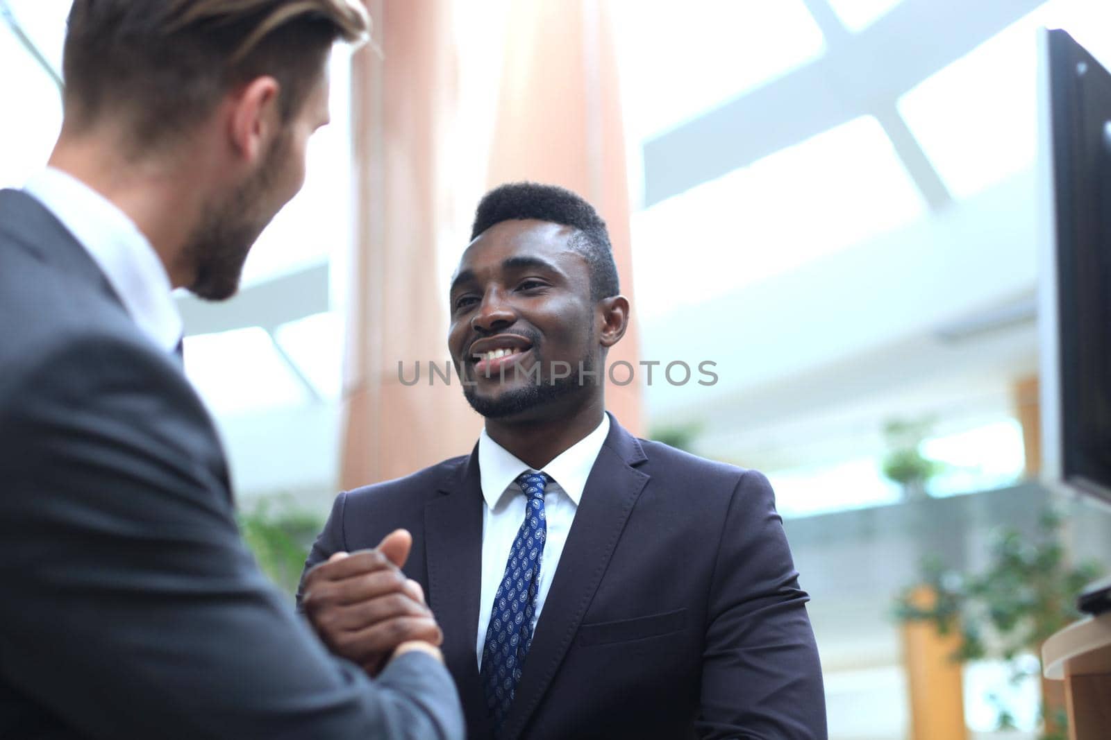 Business meeting. African American businessman shaking hands with caucasian businessman. by tsyhun