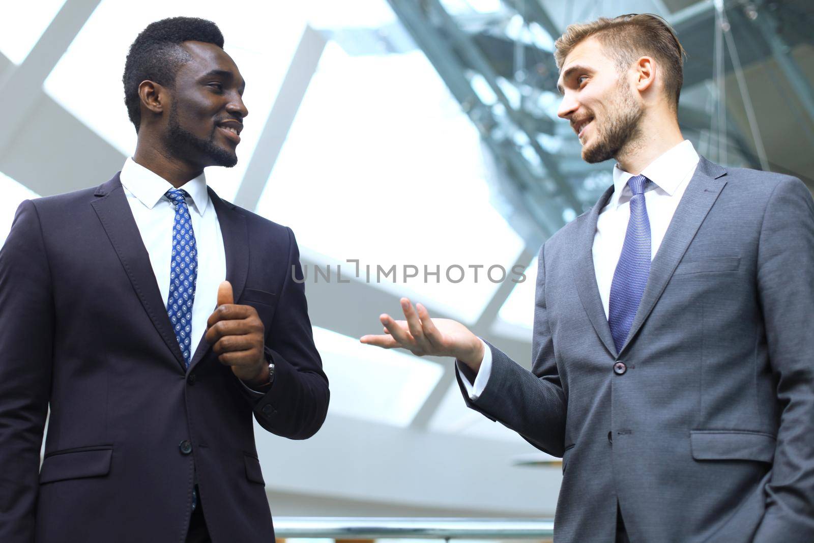 Two multinational young businessmen discussing business at meeting in office.