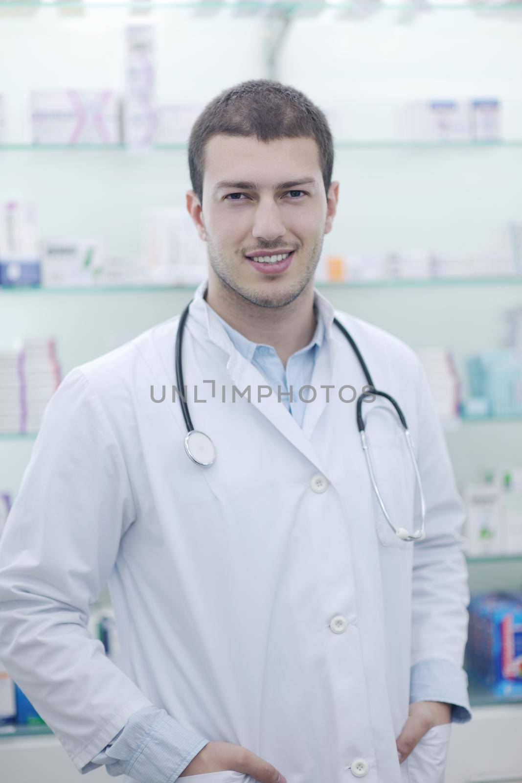 portrait of handsome young  pharmacist chemist man standing in pharmacy drugstore