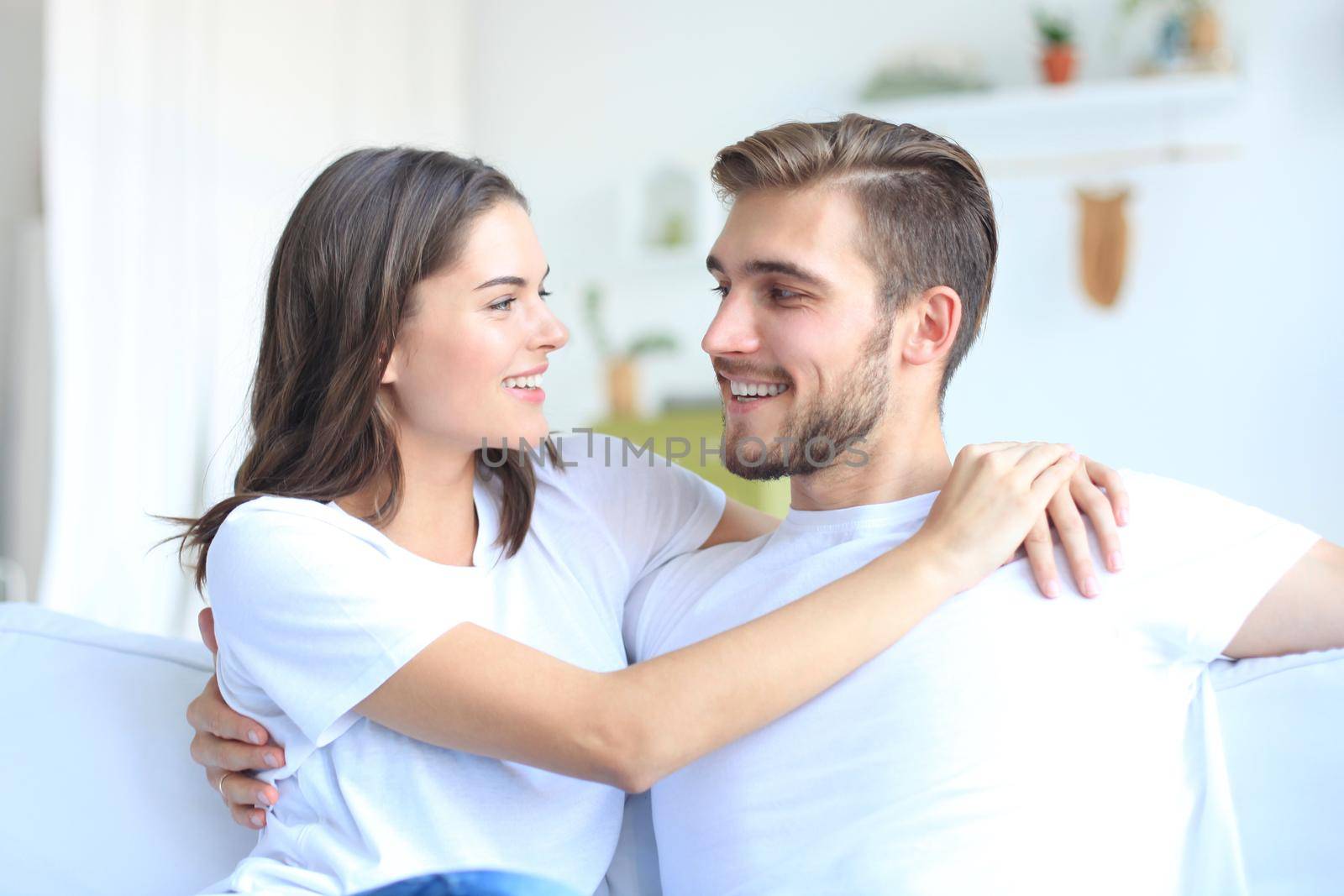 Happy young couple hugging and looking at each other at home interior. by tsyhun