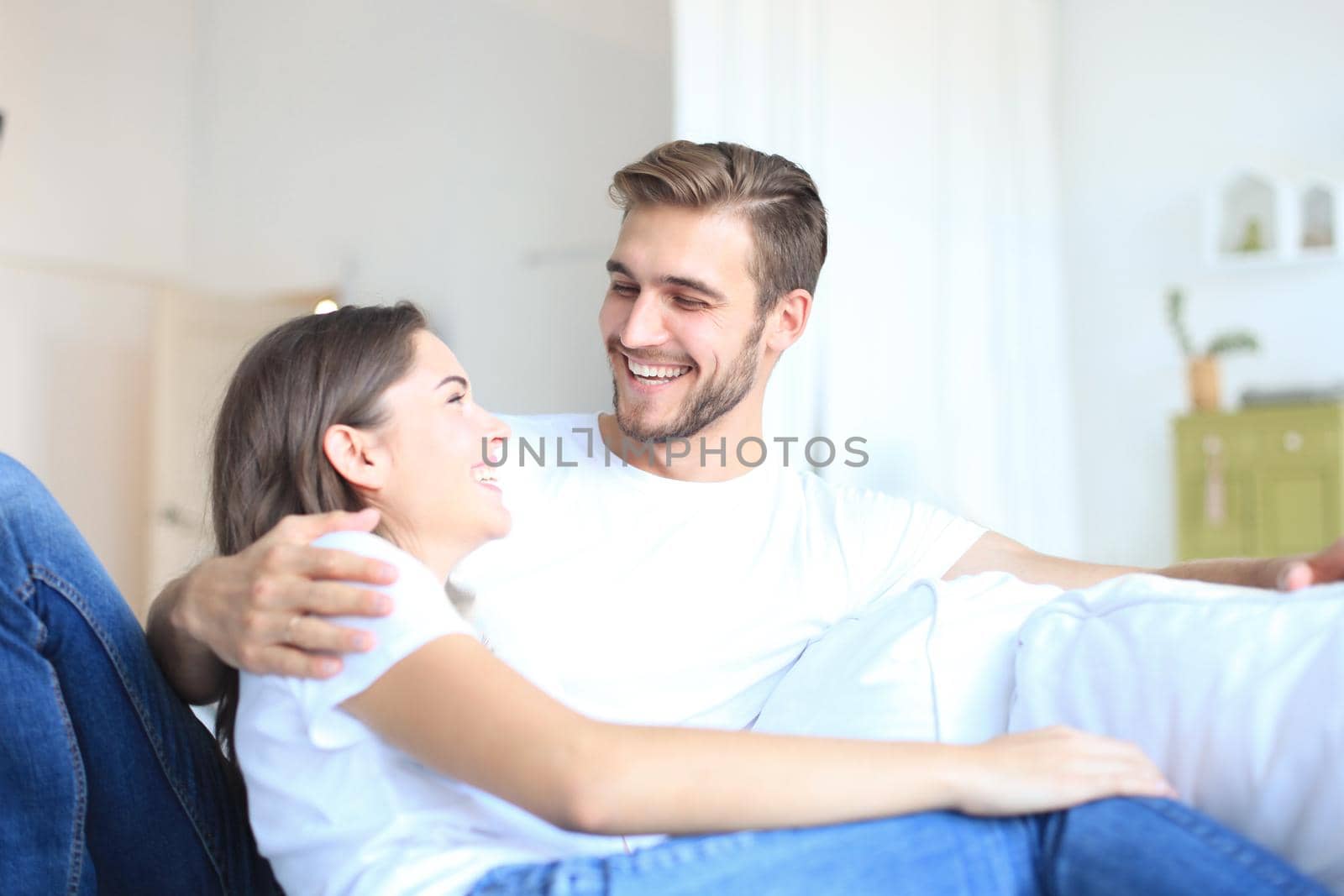 Happy young couple hugging and enjoying in a couch at home.