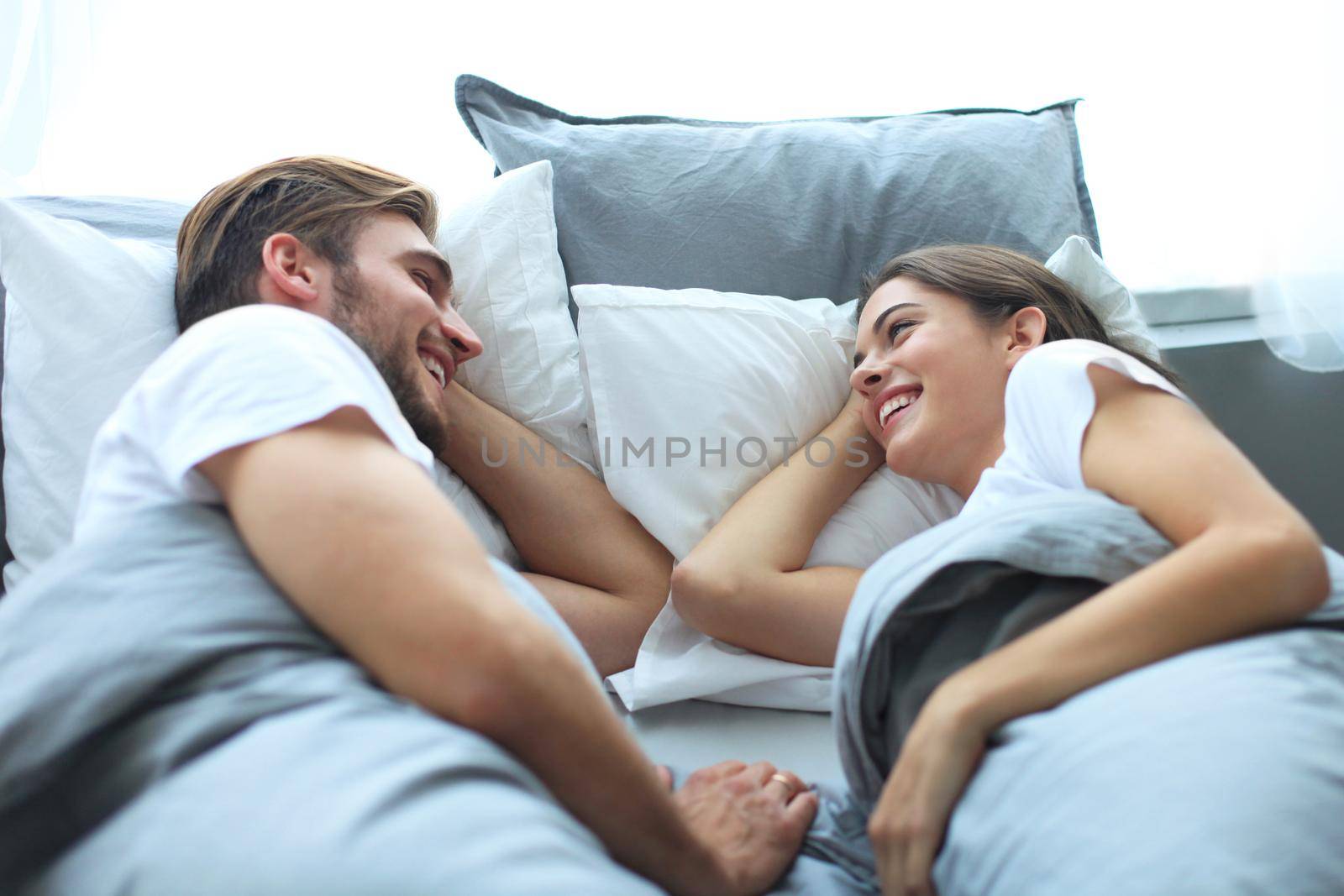 Cheerful couple awaking and looking at each other in bed.
