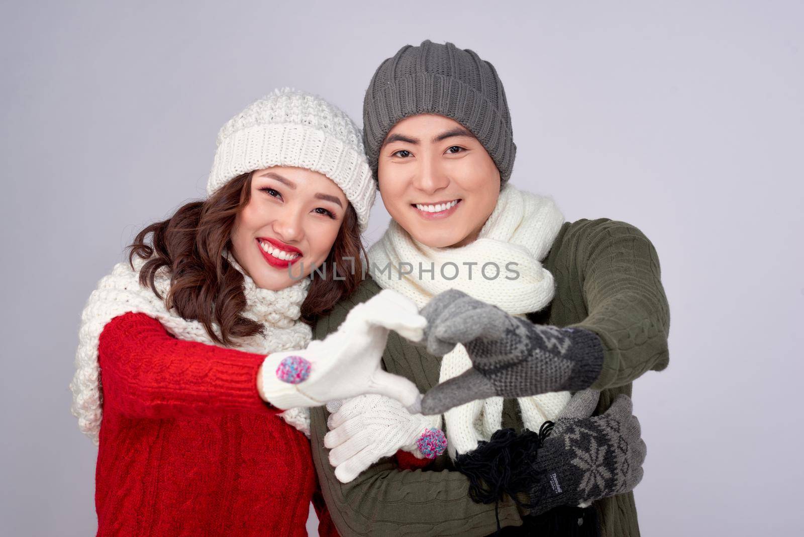 Happy young lovers in knitted woolen clothing hugging and looking together.