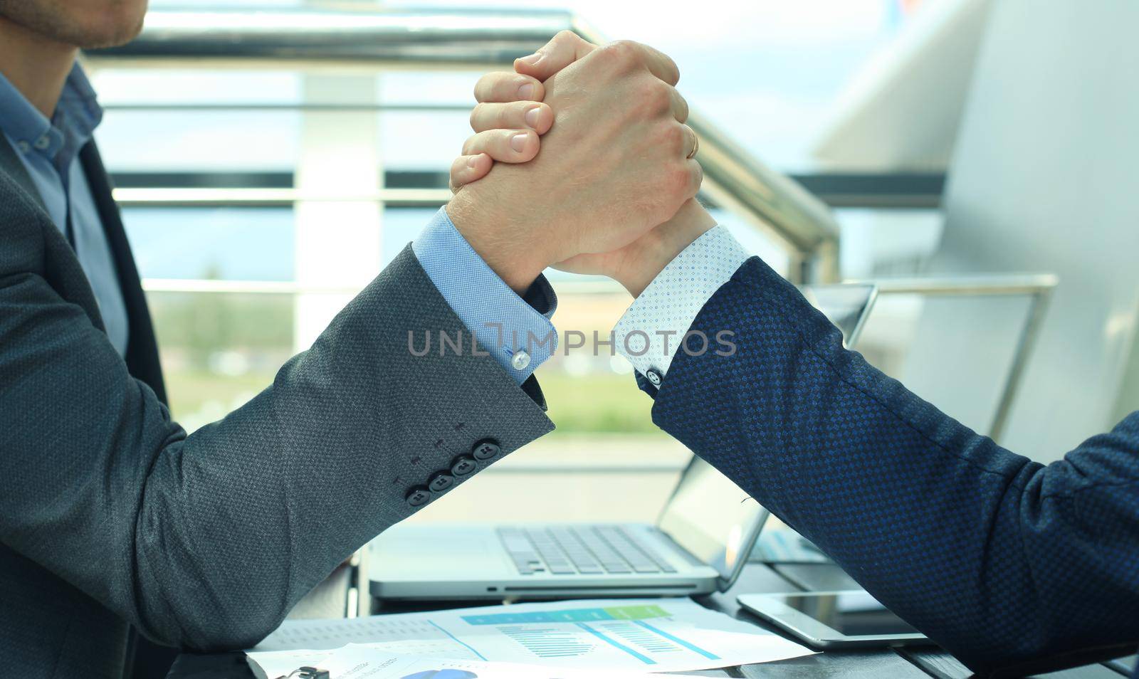 Two businessmen press hands each other on a forward background.