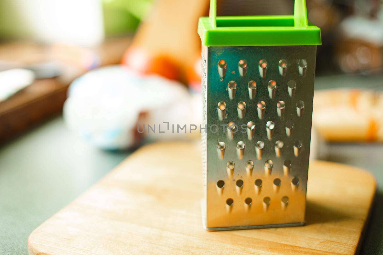 Picture of metal kitchen grater with oval holes on it on the kitchen table by StudioLucky