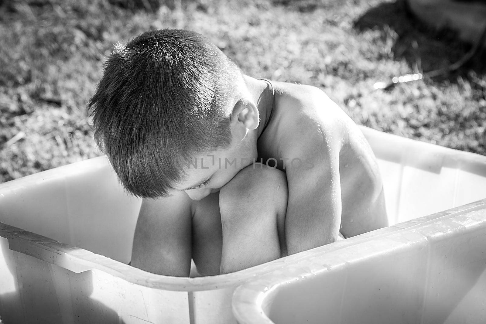Sad little boy sitting in bath black and white photo
