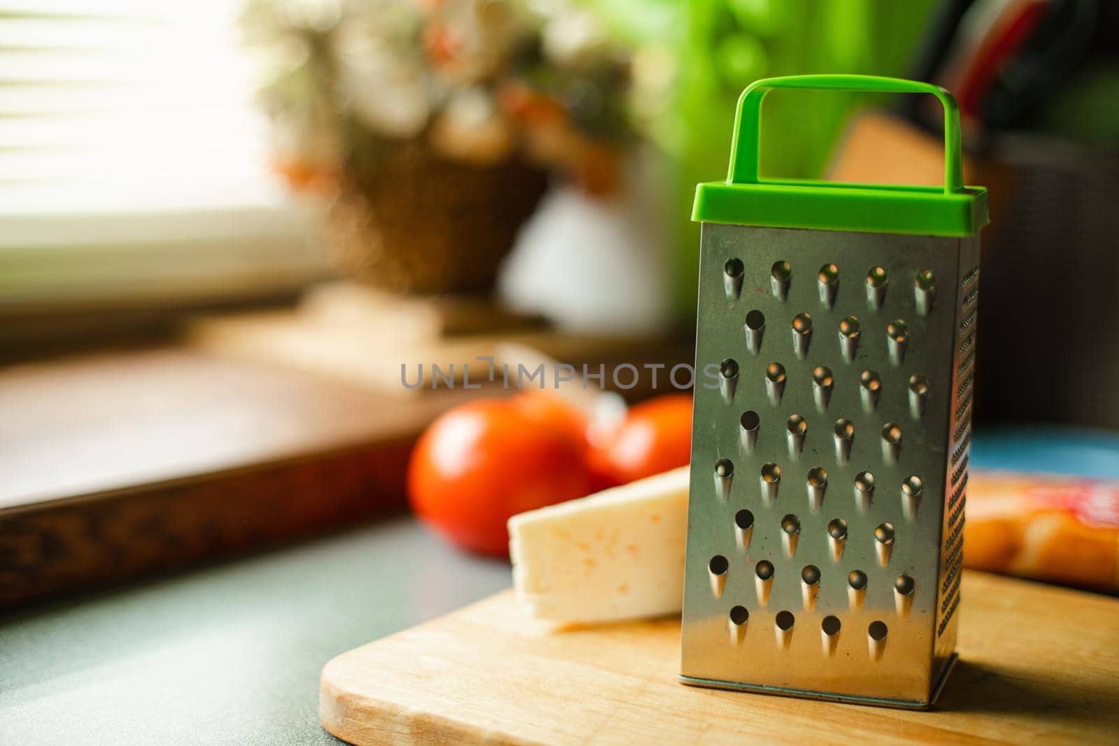 Picture of metal kitchen grater with oval holes on it on the kitchen table by StudioLucky