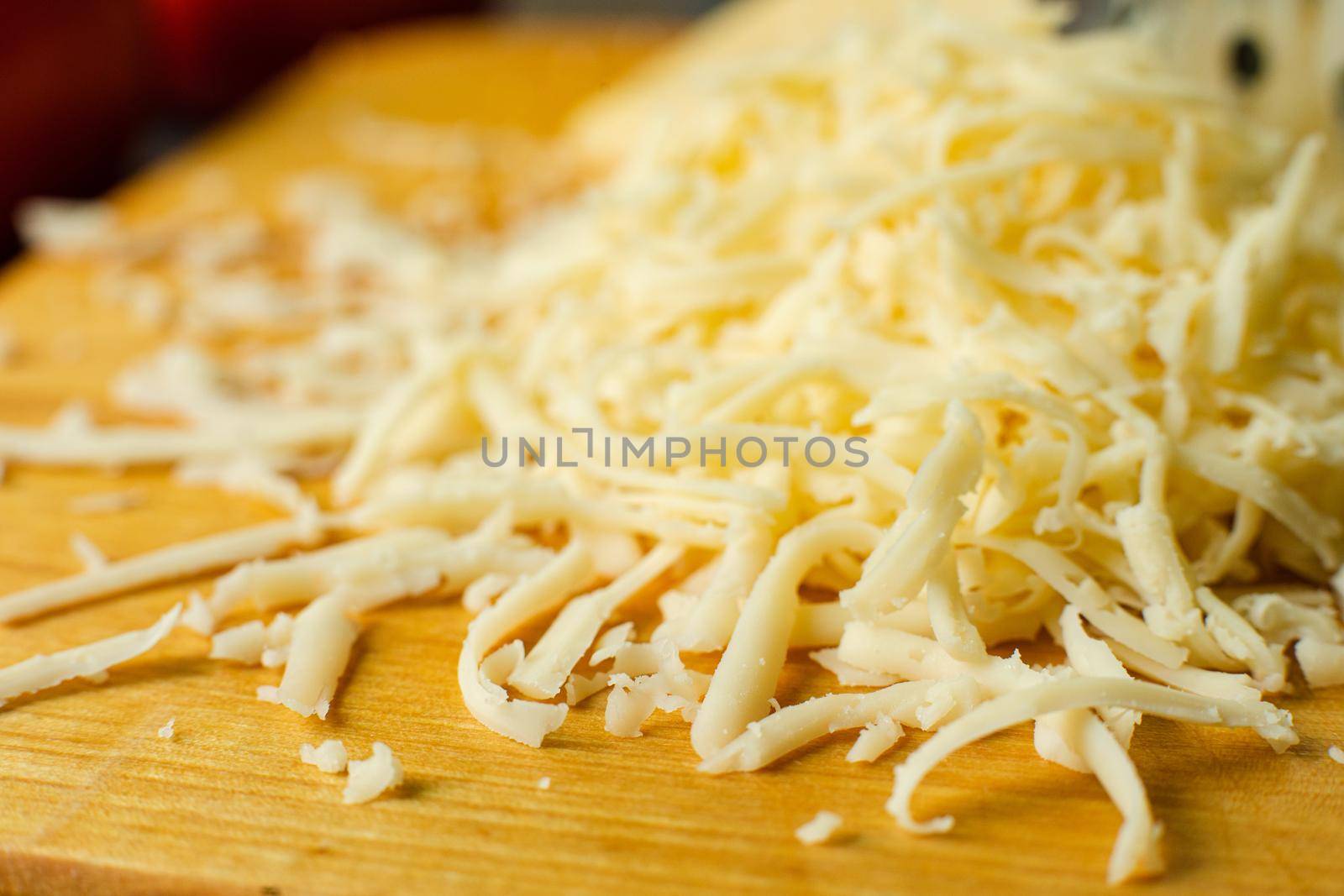 Picture of metal kitchen grater with oval holes on it on the kitchen table with cheese