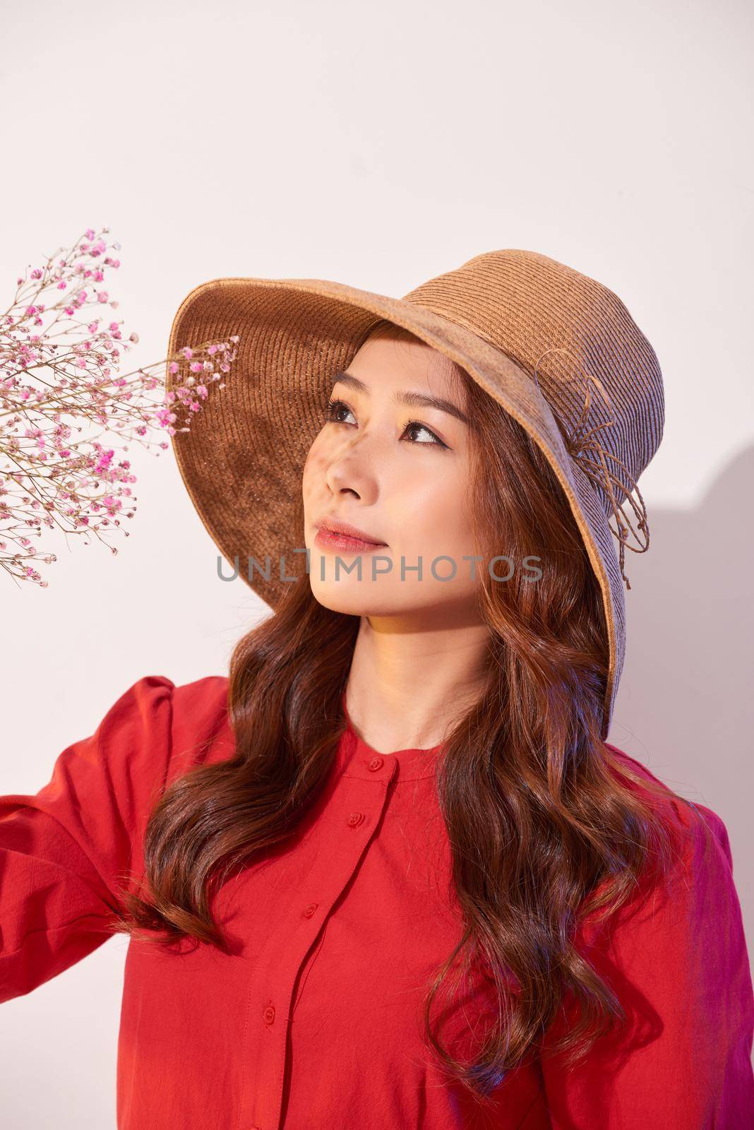 a lovely young woman in summer dress and straw hat posing while holding bouquet flowers