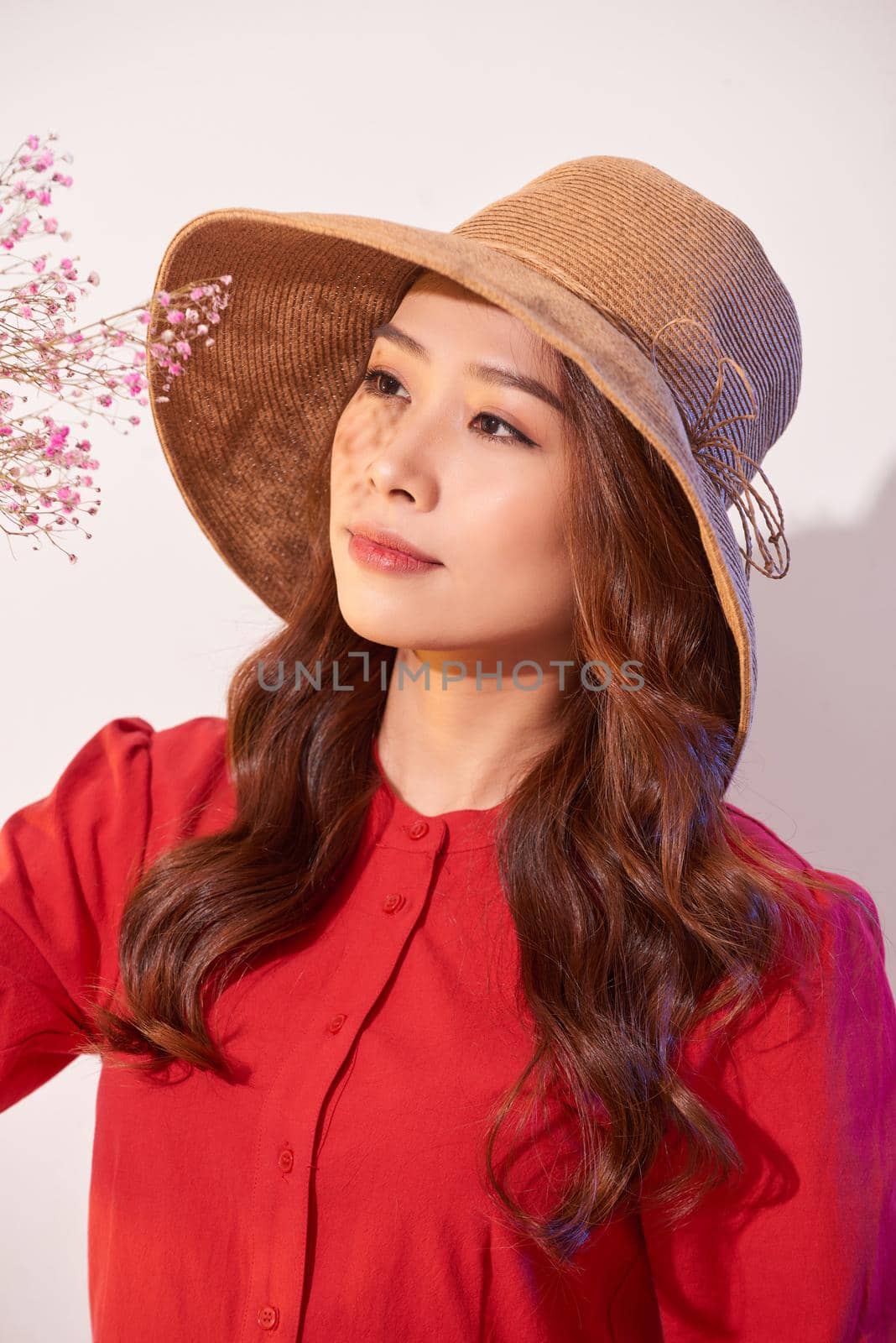 a lovely young woman in summer dress and straw hat posing while holding bouquet flowers