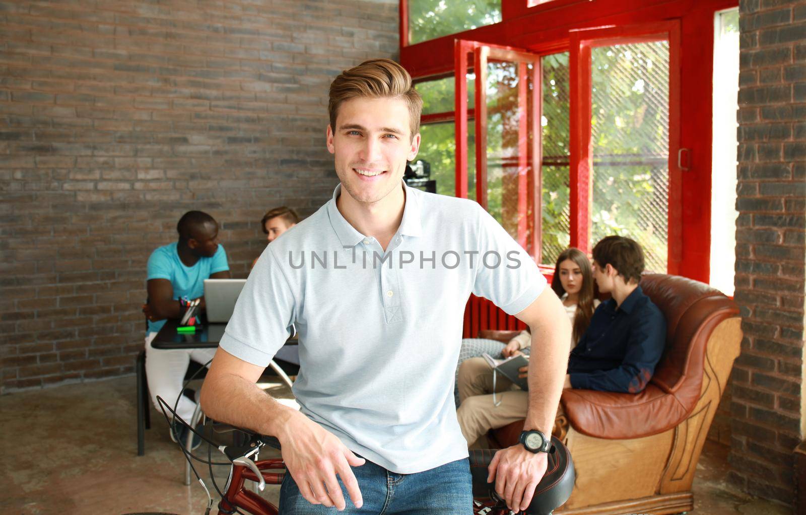 Young man sitting on a bicycle in a modern office by tsyhun