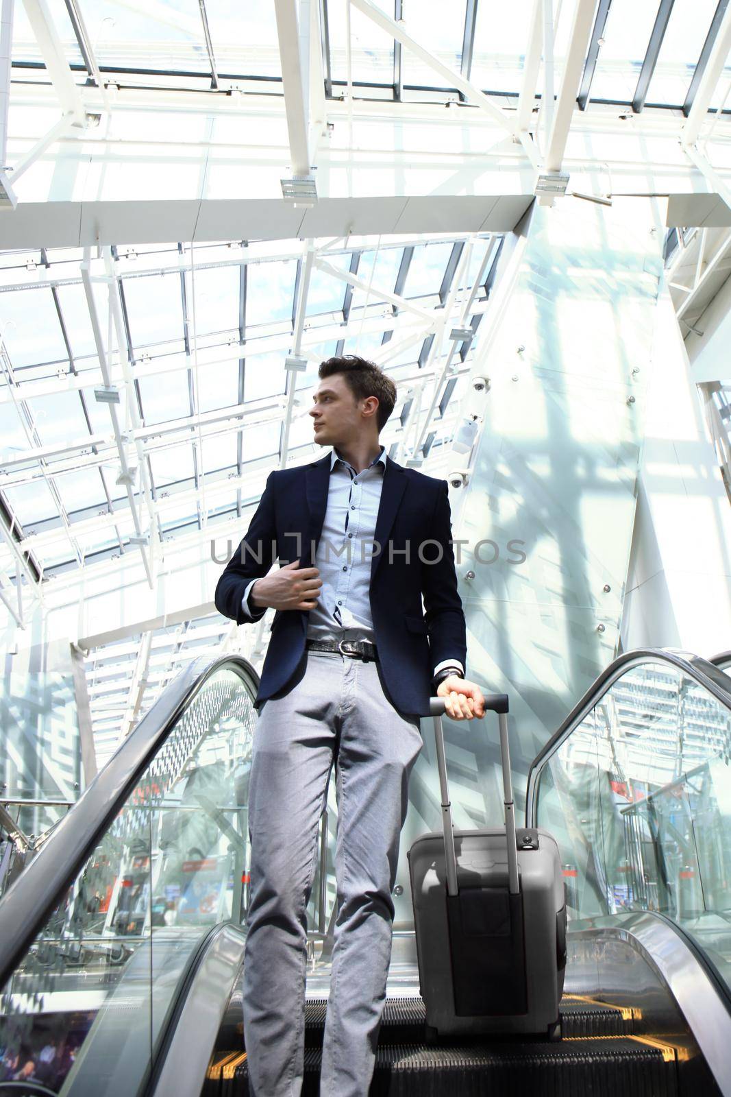 Businessman at the airport going down the escalator.