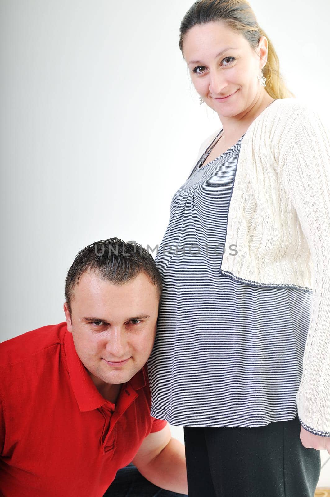 young family couple together in studio isolated on white. happy and waiting for baby