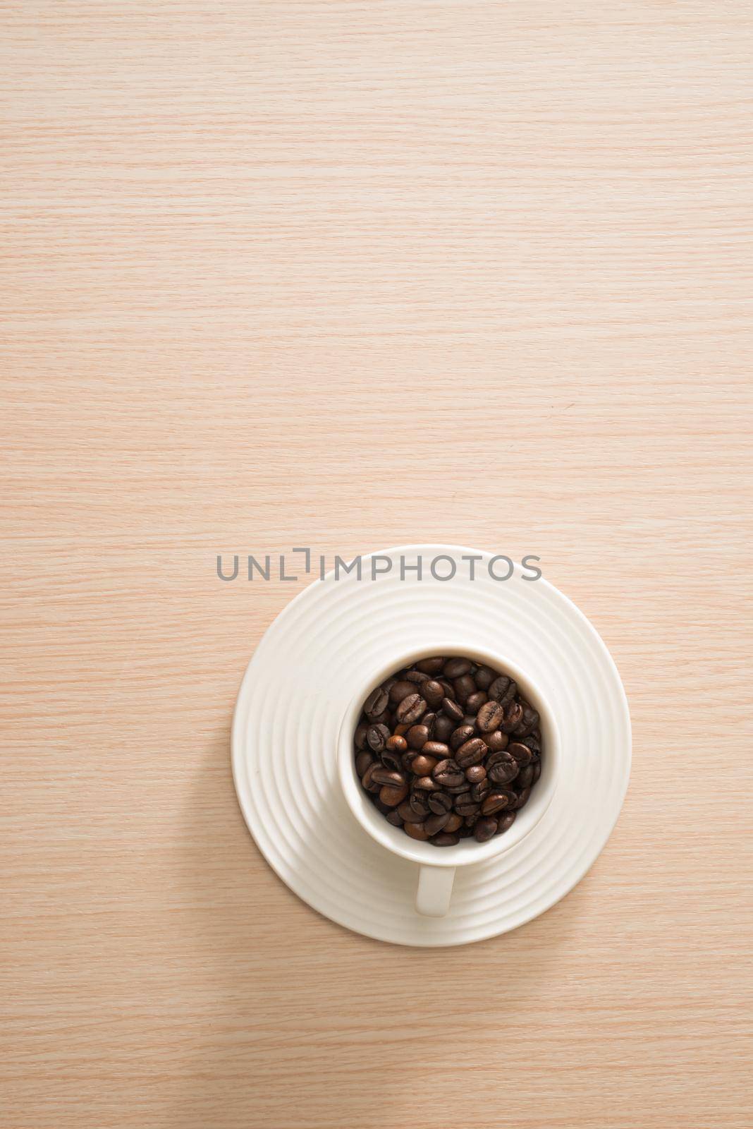 Cup of full coffee beans on the wood background