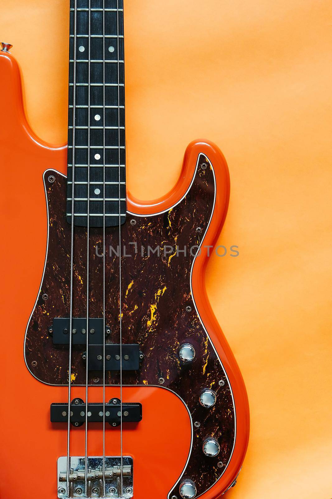orange electric bass guitar on orange background with copy space