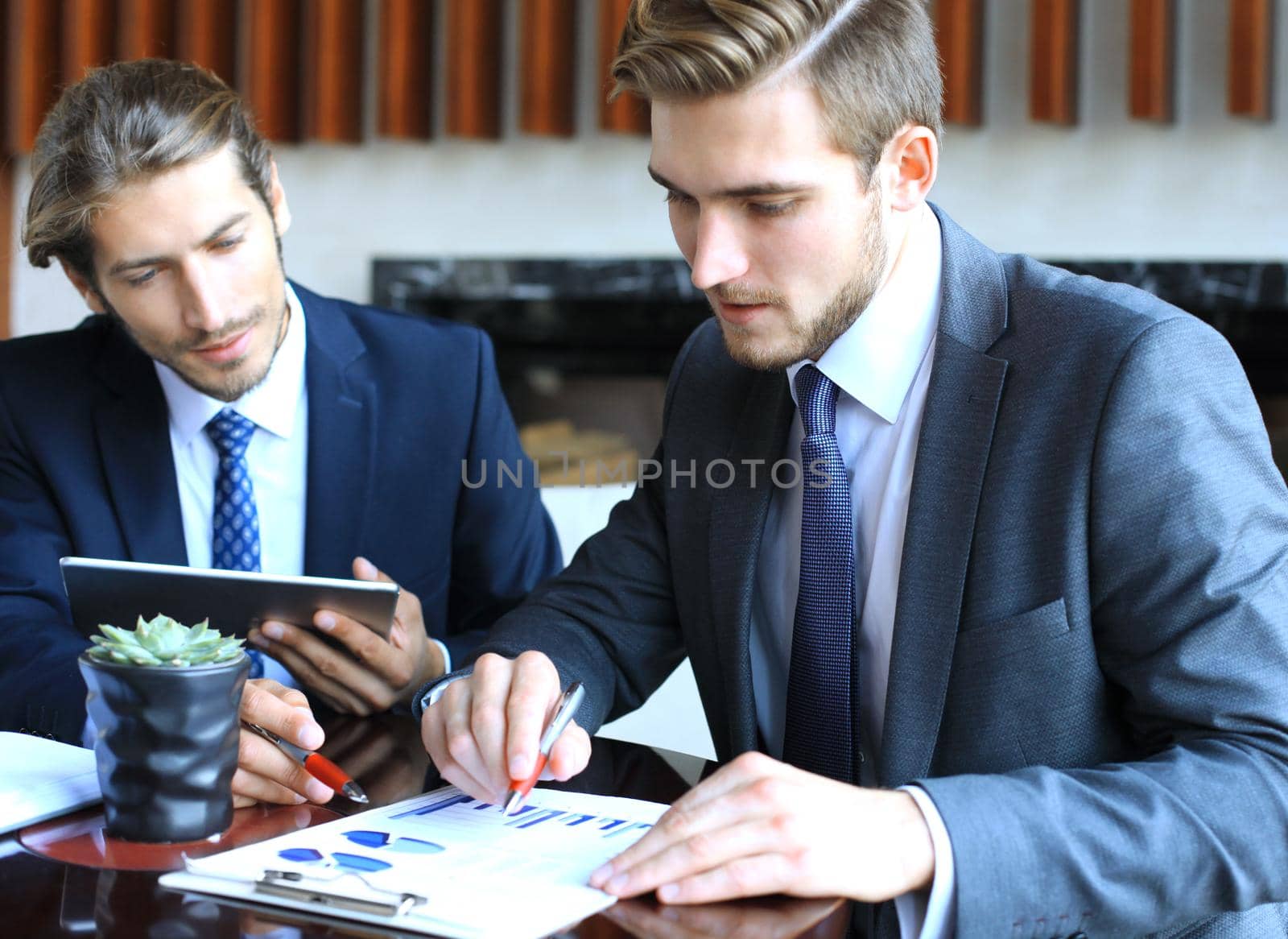 Two young businessmen analyzing financial document at meeting. by tsyhun