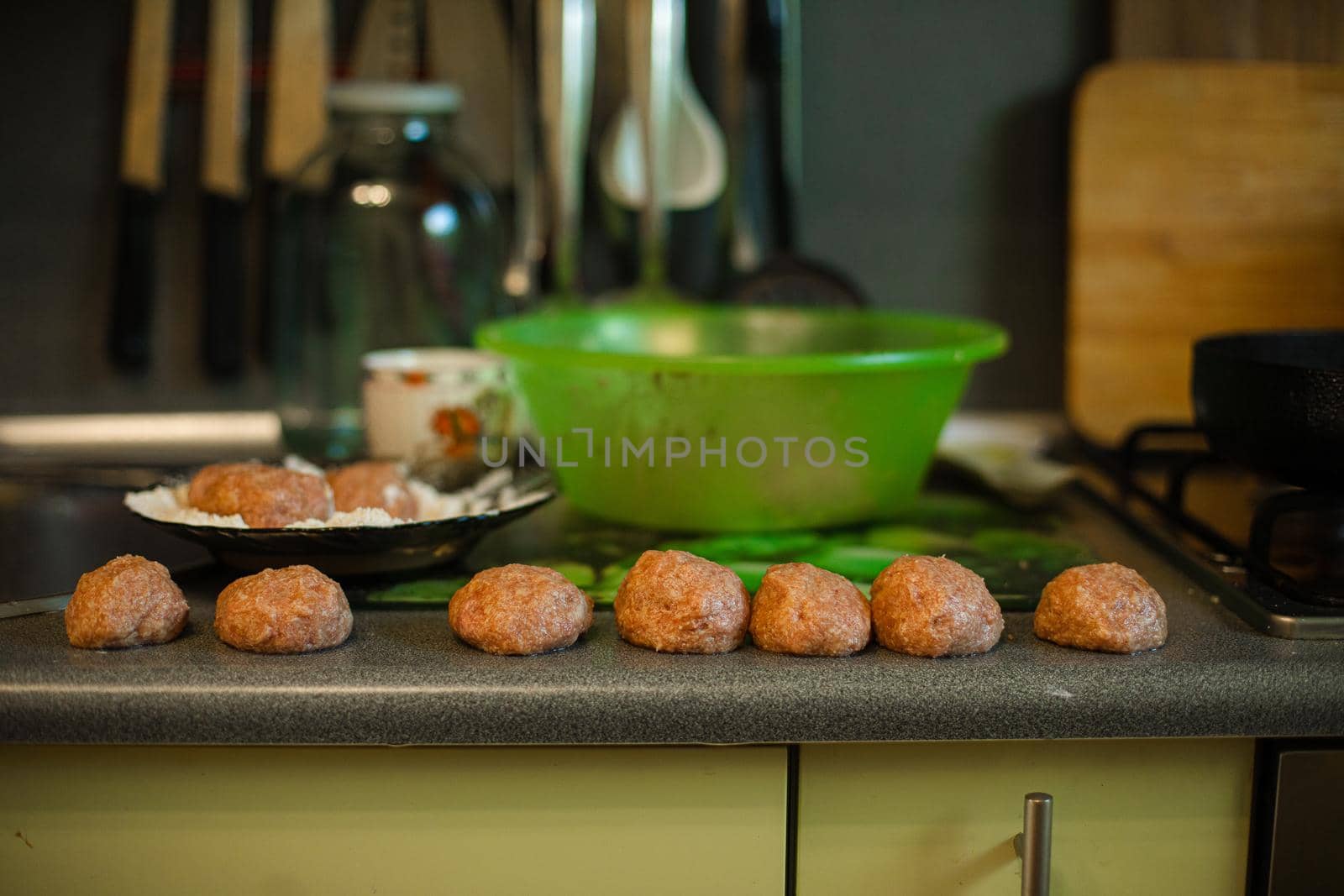 Cooking meatballs, ready mince lies by roasting on the kitchen table in big light kitchen