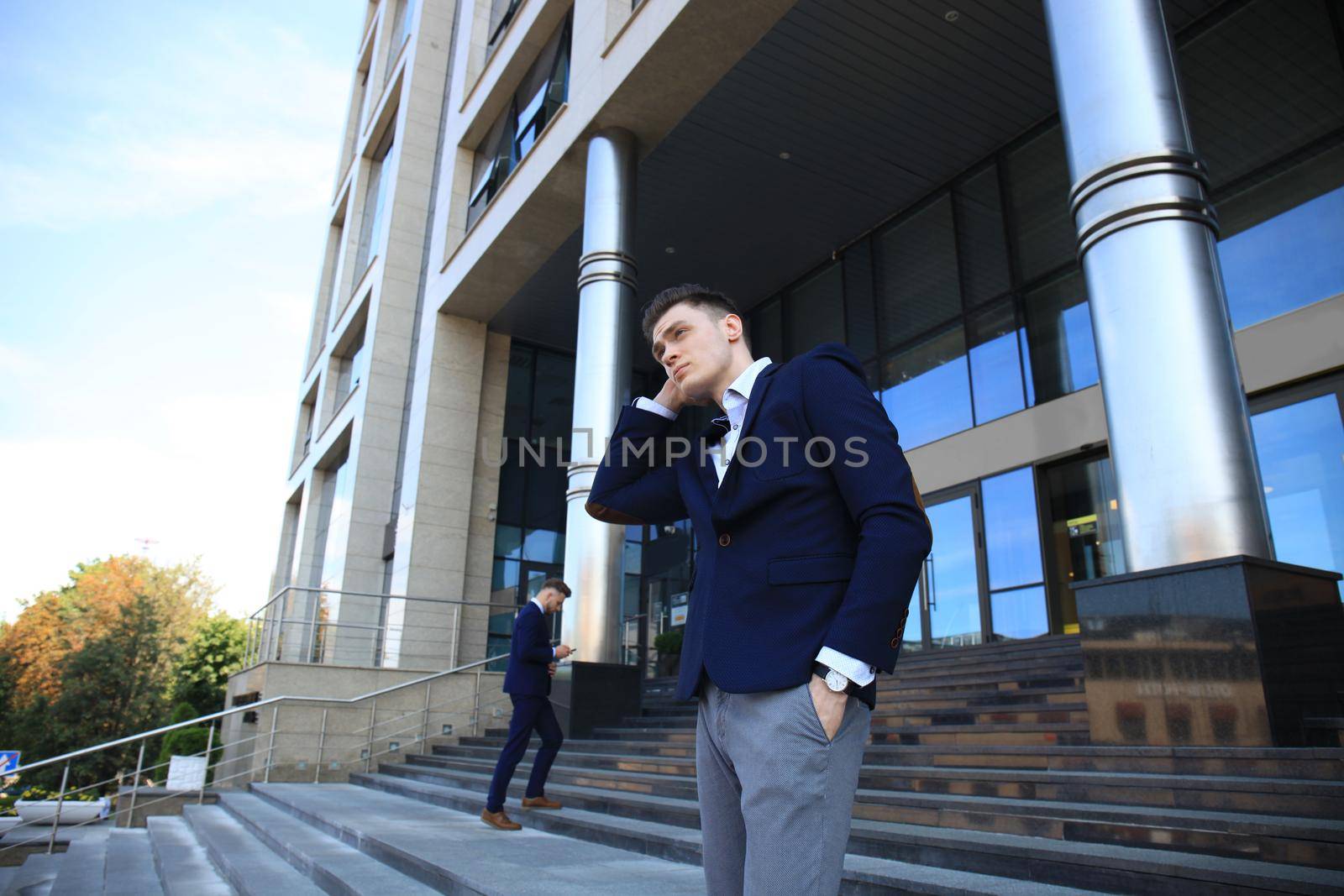 Portrait of a handsome businessman in a suit standing outside a city building.