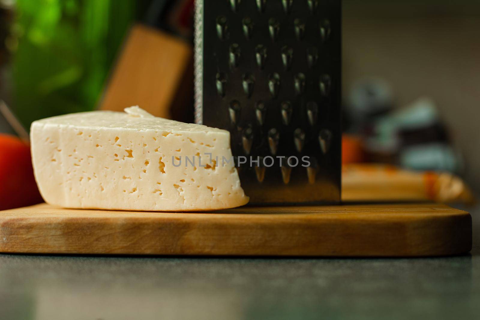 Picture of metal kitchen grater with oval holes on it on the kitchen table by StudioLucky