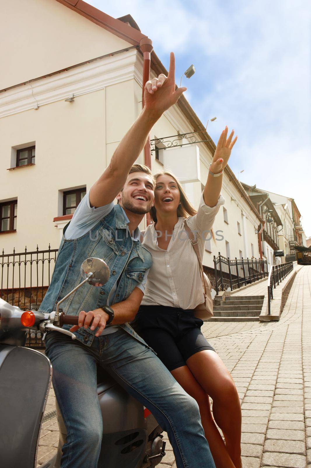 happy young couple riding scooter in town. Handsome guy and young woman travel. Adventure and vacations concept. by tsyhun