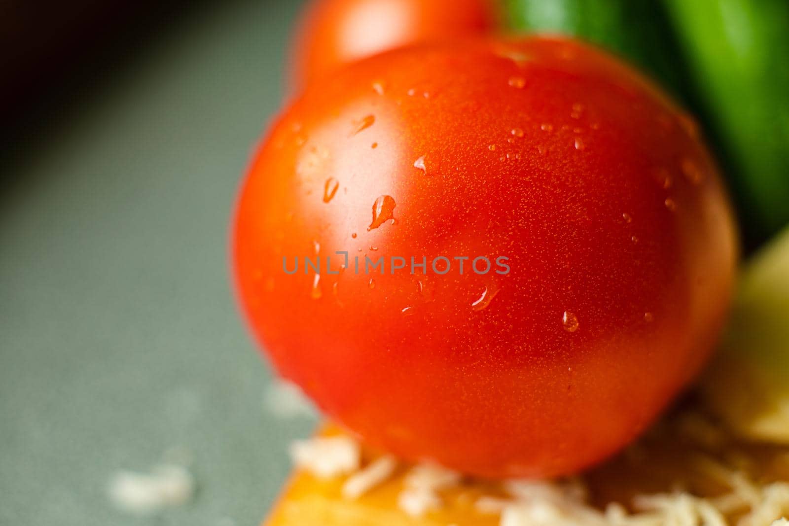 A washed pure red tomato lies on the table with drops of water on it by StudioLucky