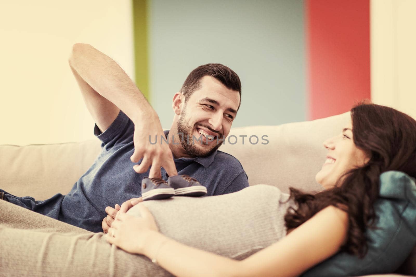 young pregnant couple relaxing on sofa by dotshock