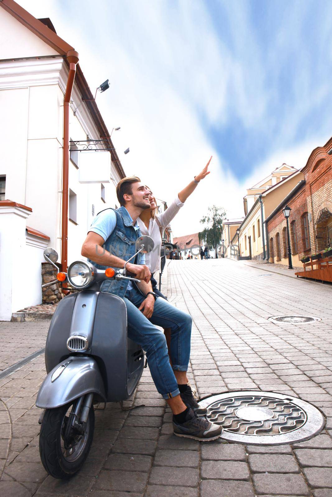 happy young couple riding scooter in town. Handsome guy and young woman travel. Adventure and vacations concept.