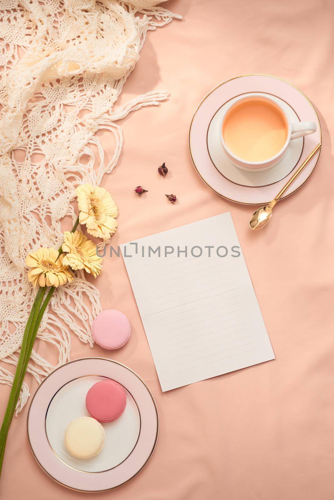 Envelope, flowers, and macarons with cup of tea on light background by makidotvn