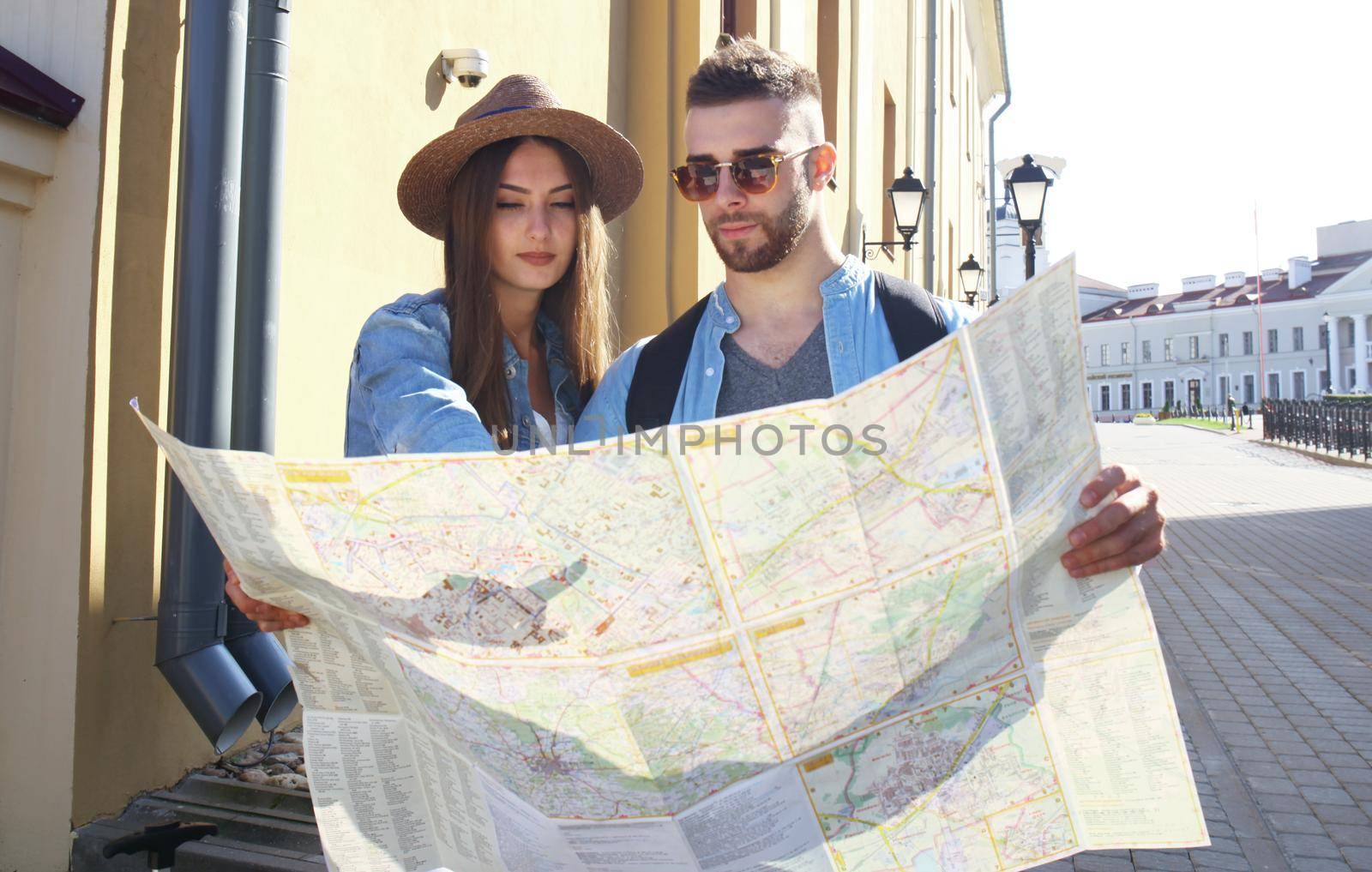 Happy couple walking outdoors sightseeing and holding a map.