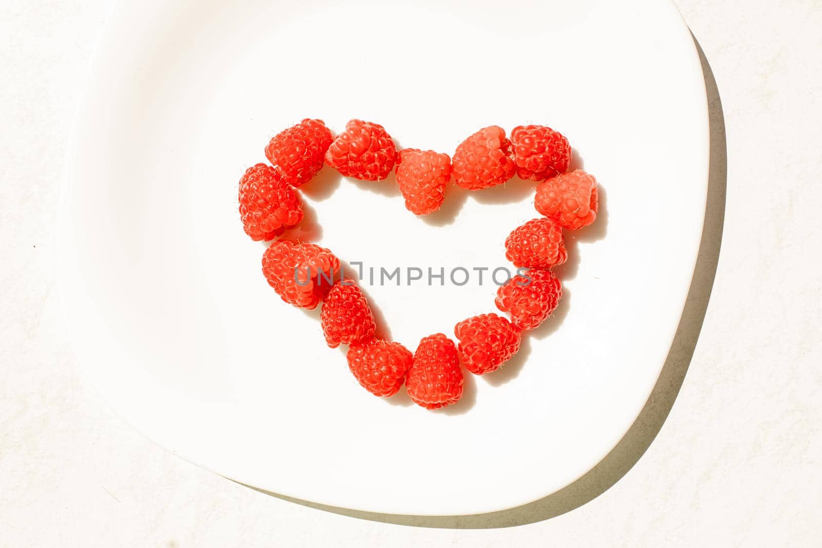 Raspberries in shape of heart. Concept of love. Juicy raspberries dessert. by StudioLucky