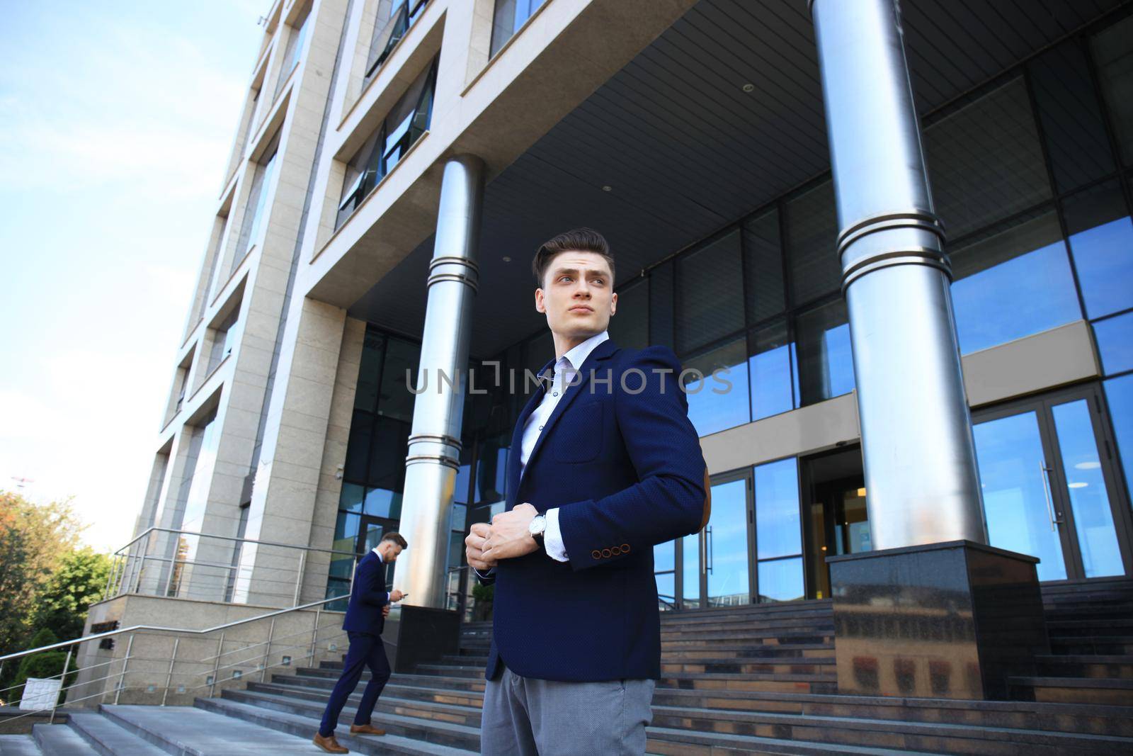 Portrait of a handsome businessman in a suit standing outside a city building. by tsyhun