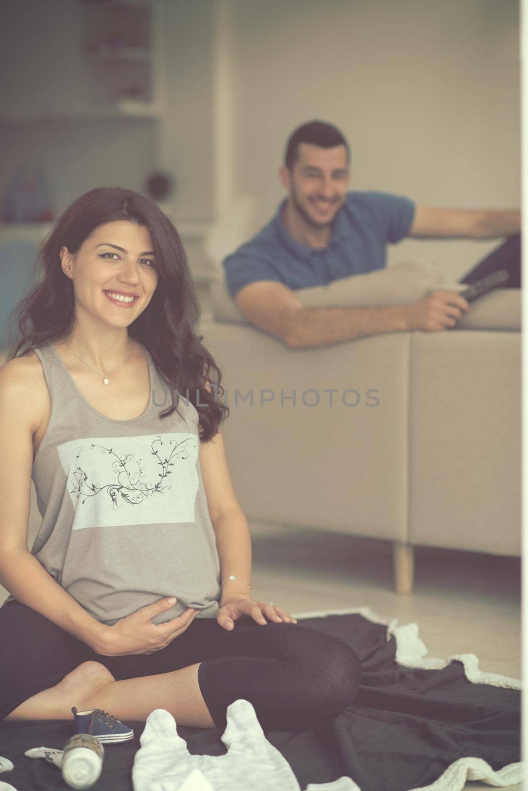 a happy pregnant couple checking a list of things for their unborn baby at home on the floor