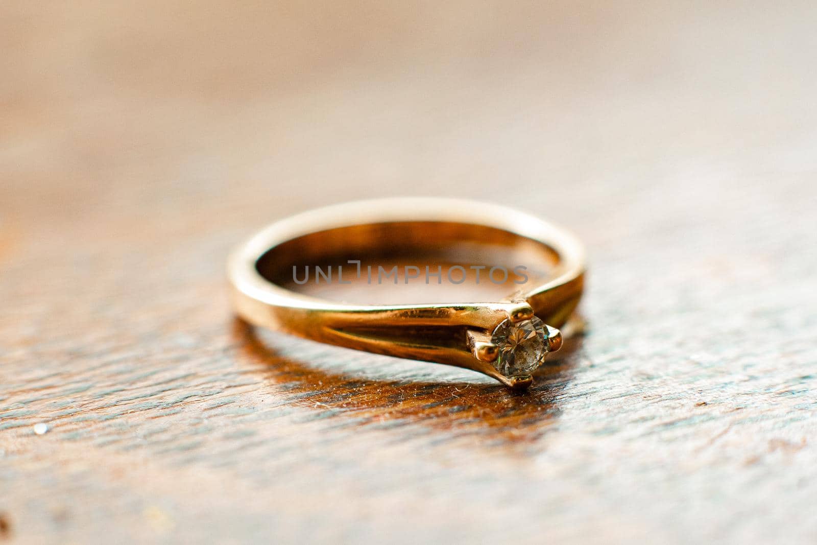 Small, neat diamond engagement ring on the wooden table by StudioLucky