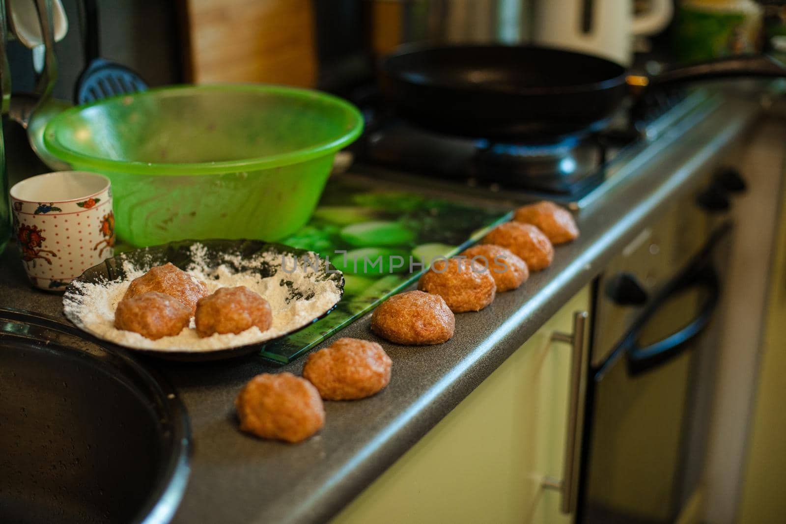 Cooking meatballs, ready mince lies by roasting on the kitchen table in big light kitchen