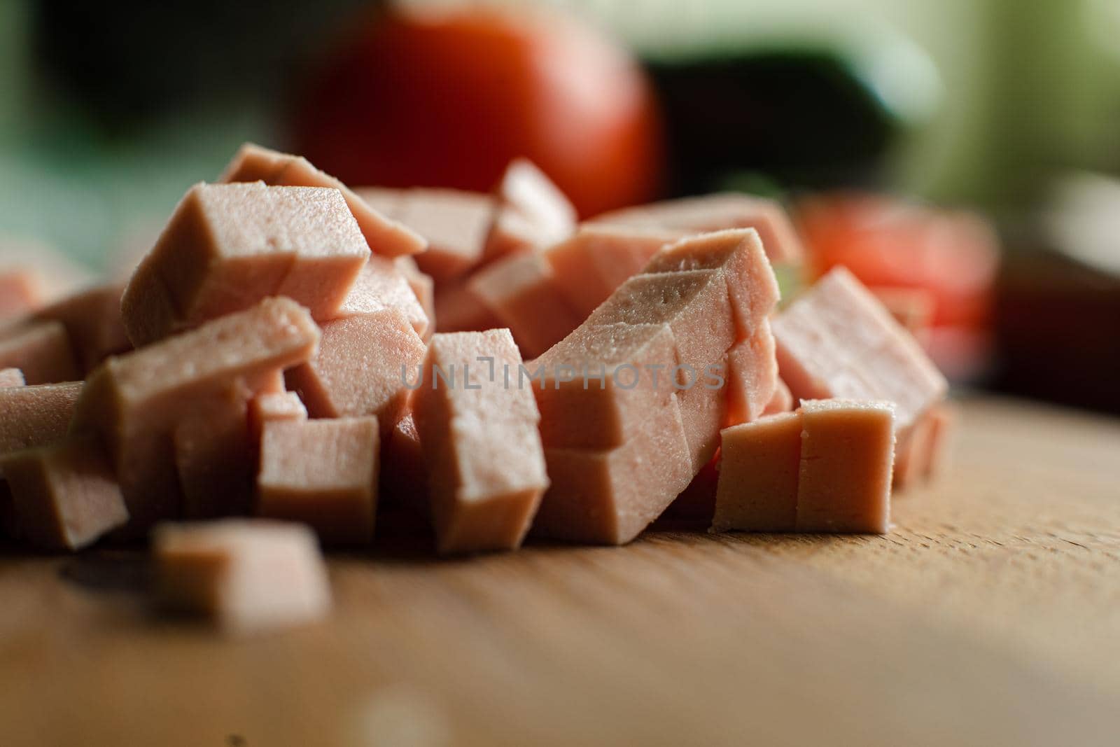 Picture of a small pile of cube sliced sausage for cooking on a wooden table in the kitchen